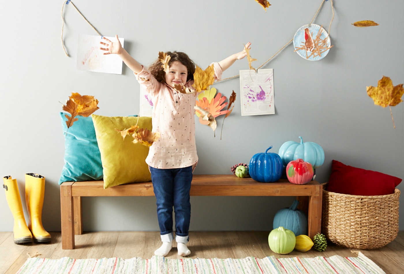 child-throwing-leaves-in-thanksgiving-decorated-home